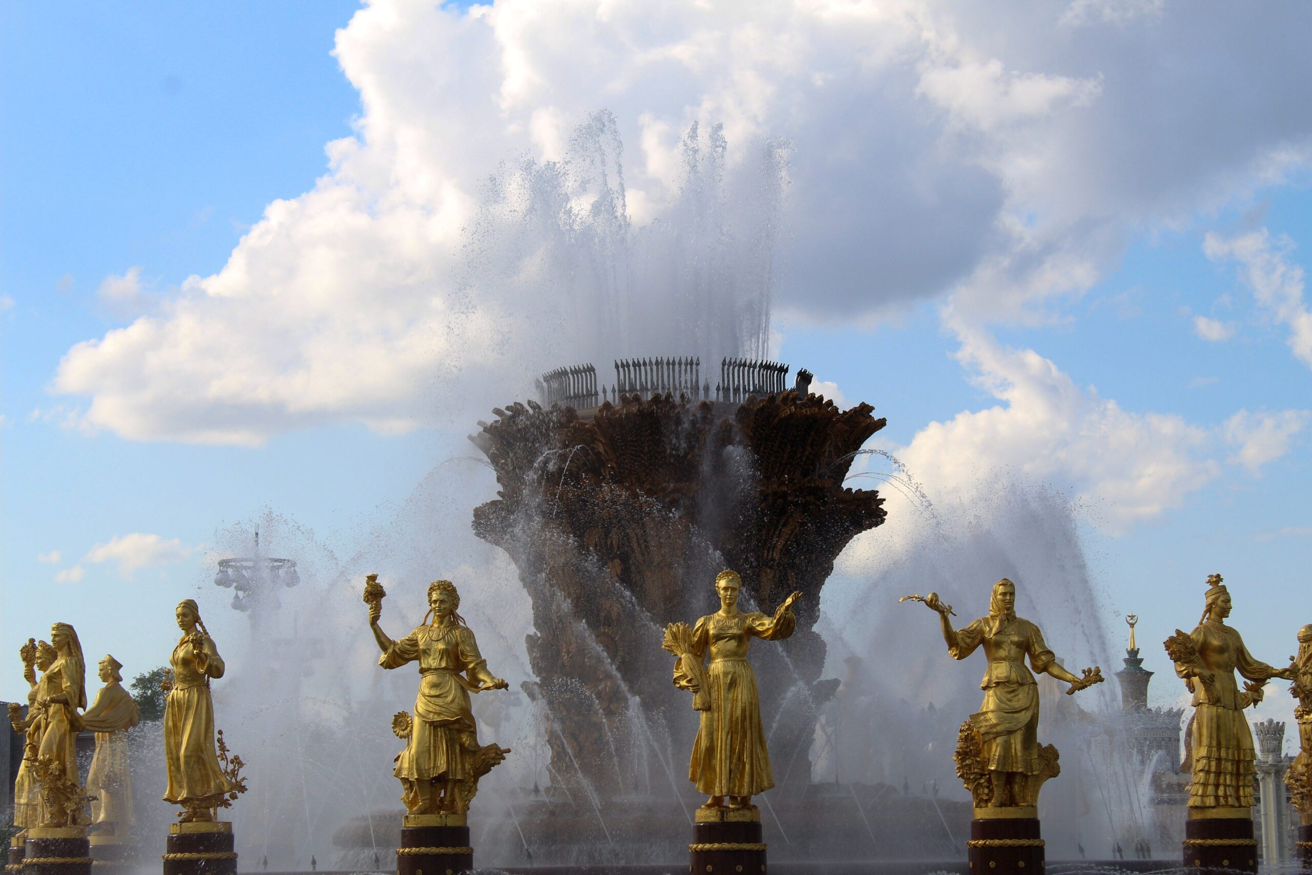Stunning fountain with golden statues under a blue sky at VDNKh, showcasing artistic craftsmanship.